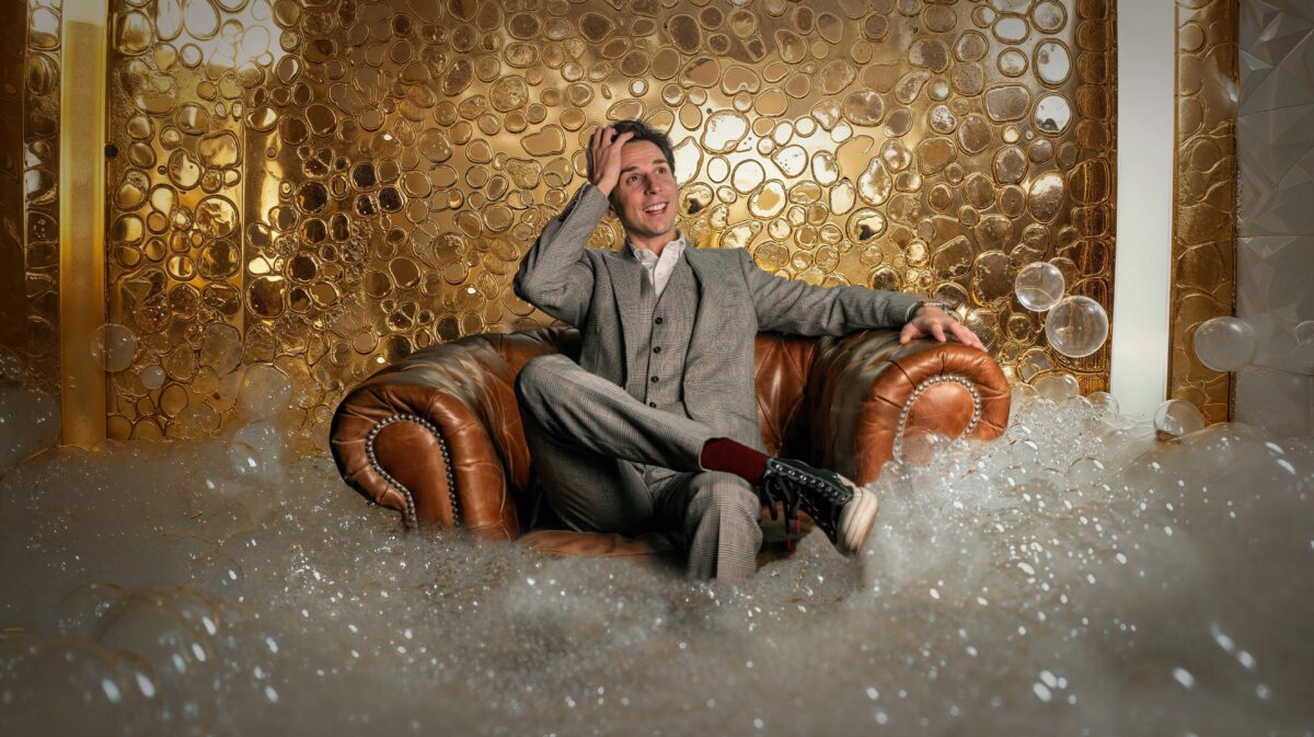 Cyril Regard dans un fauteuil Chesterfield, devant un mur de bulles dorées