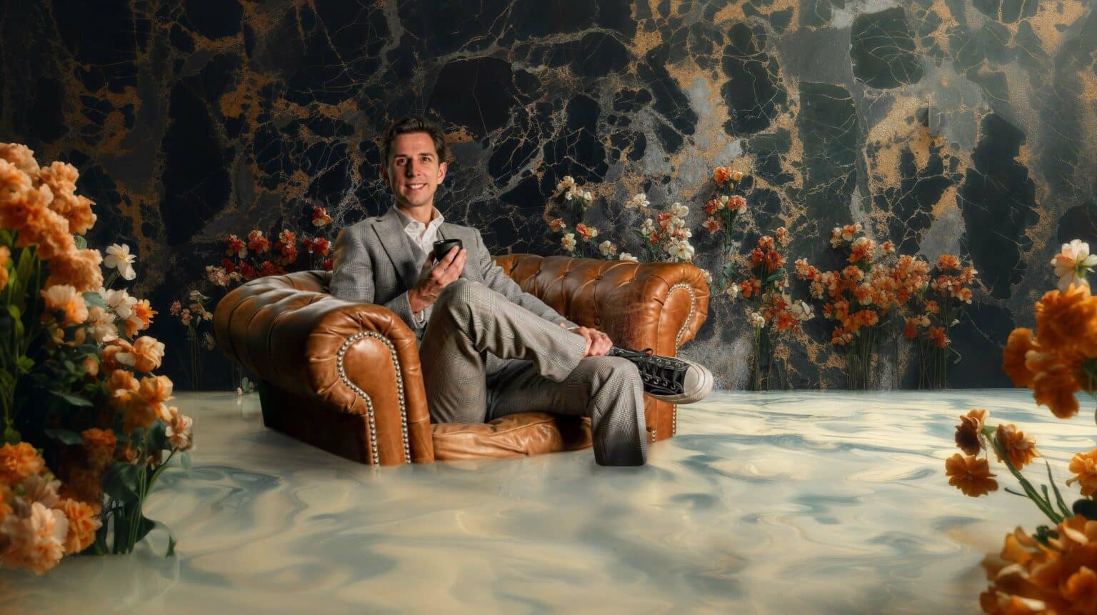 Cyril Regard dans un fauteuil Chesterfield, une tasse à la main, entouré de fleurs