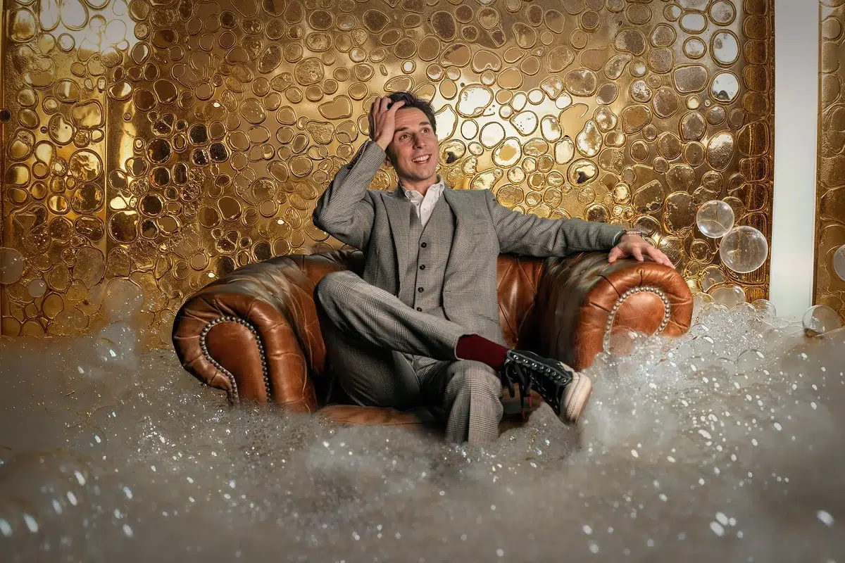 Cyril Regard dans un fauteuil Chesterfield, devant un mur de bulles dorées